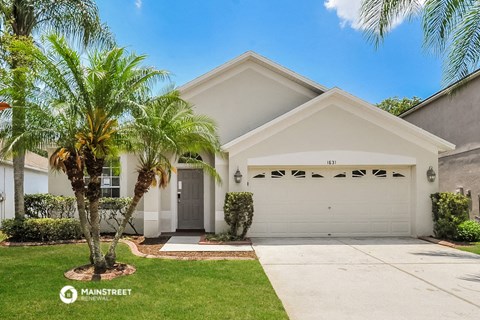 a white house with a garage door and palm trees