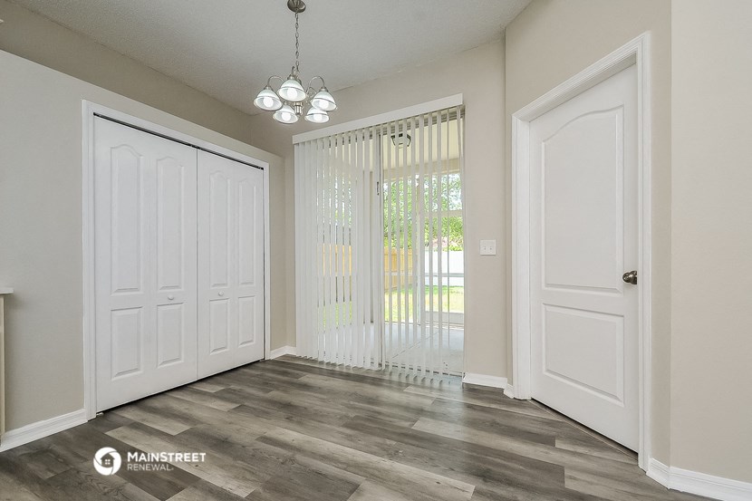 an empty living room with white doors and a window