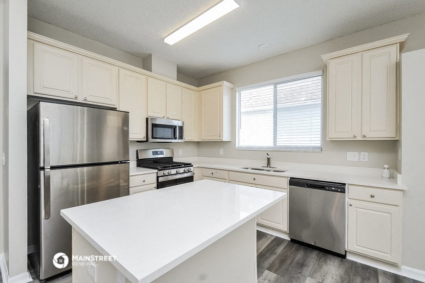 a white kitchen with stainless steel appliances and white counter tops