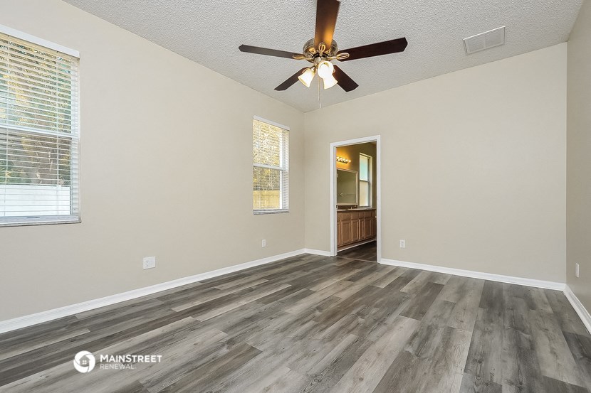 the spacious living room with wood floors and a ceiling fan