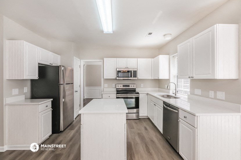 a white kitchen with stainless steel appliances and white cabinets