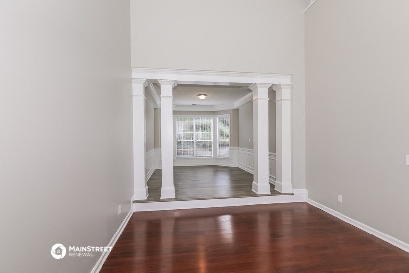 an empty living room with wood floors and white columns