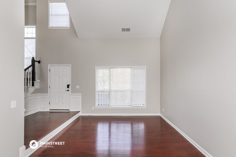 an empty living room with wood floors and white walls