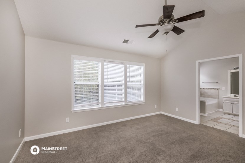 an empty living room with a ceiling fan and a large window