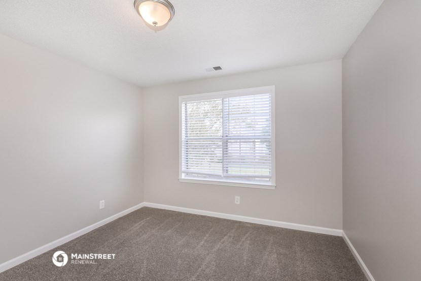 the spacious living room of a manufactured home with carpet and a window