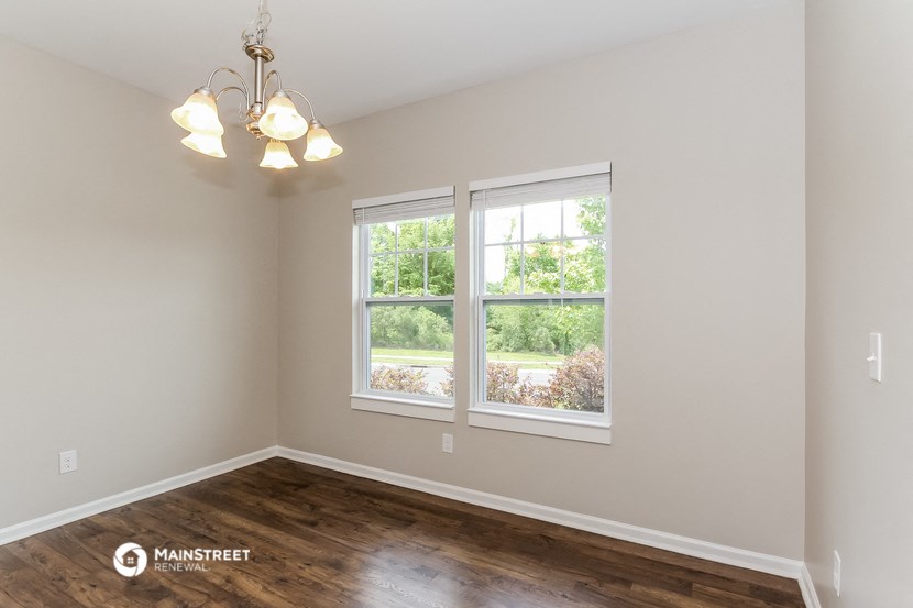 the living room of a home with a wood floor and two windows