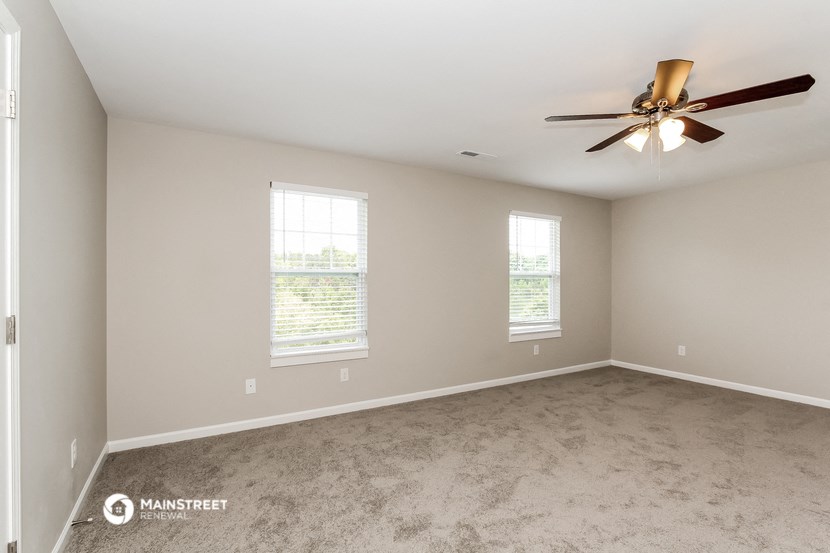 the spacious living room with carpet and a ceiling fan
