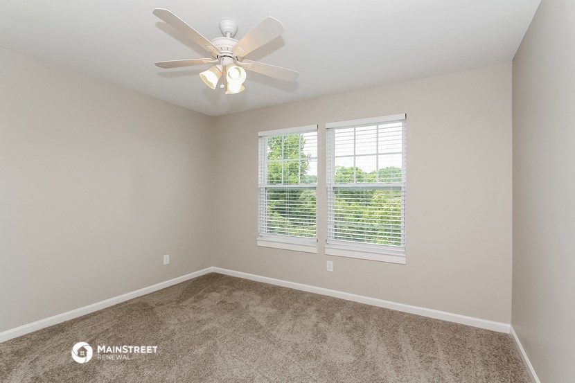 an empty bedroom with a ceiling fan and a window