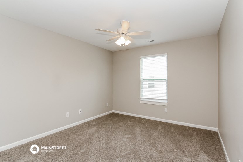 a bedroom with carpet and a ceiling fan and a window