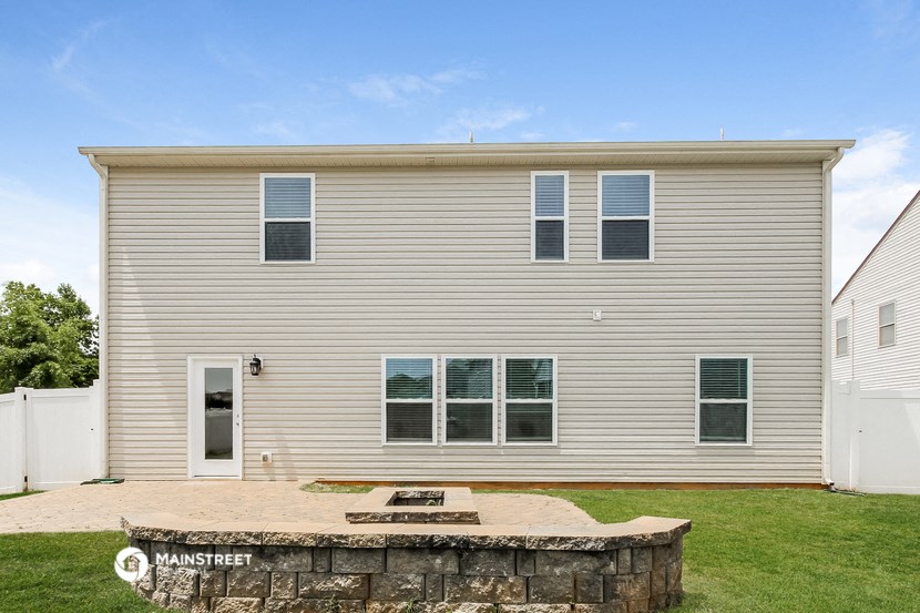 a backyard patio with a stone wall in front of a house