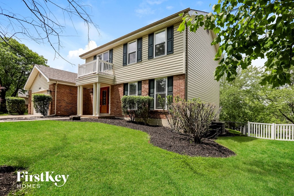 A house with a well-kept lawn and a white picket fence.