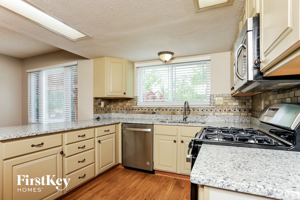 A kitchen with a stove, sink, and cabinets.
