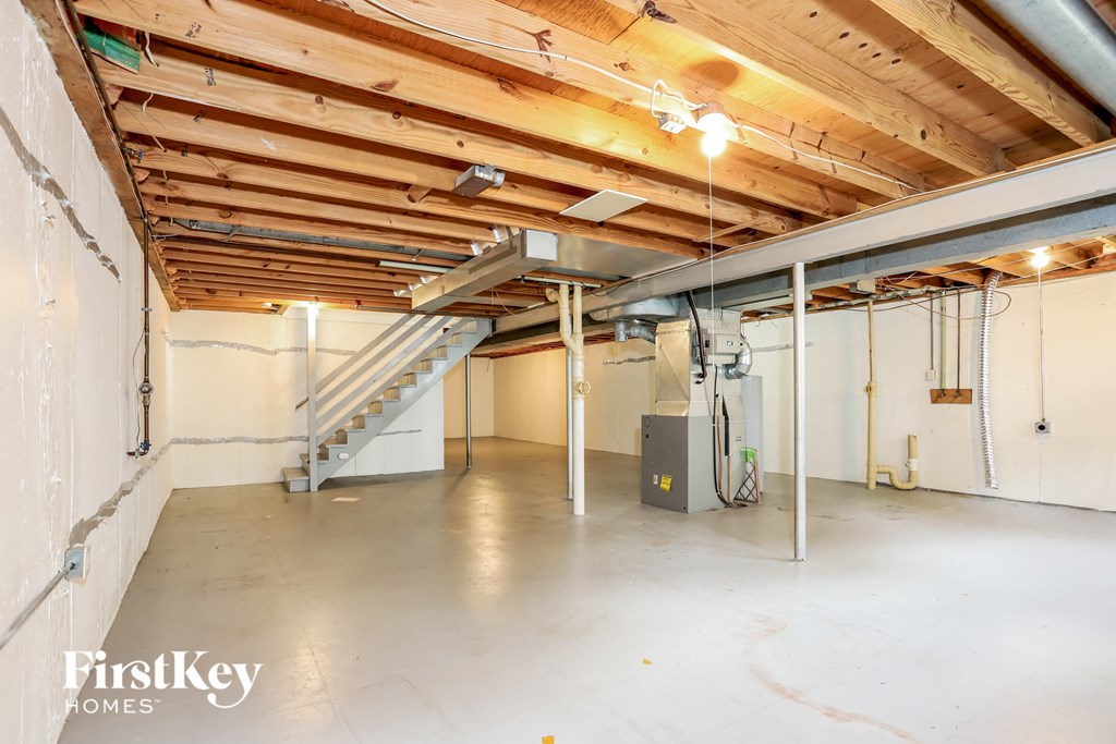 A spacious, empty room with a staircase and a heating unit.