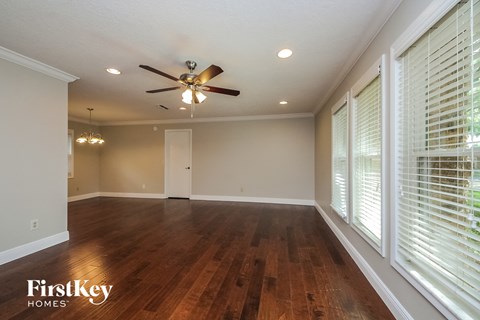 A spacious room with wooden floors and a ceiling fan.