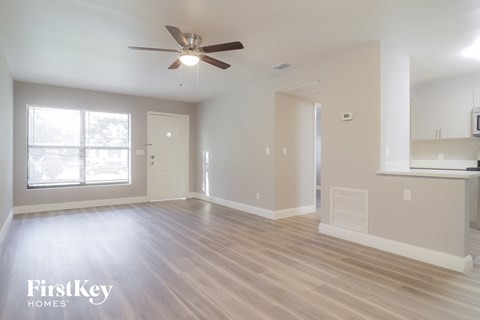 an empty living room with a ceiling fan and a window
