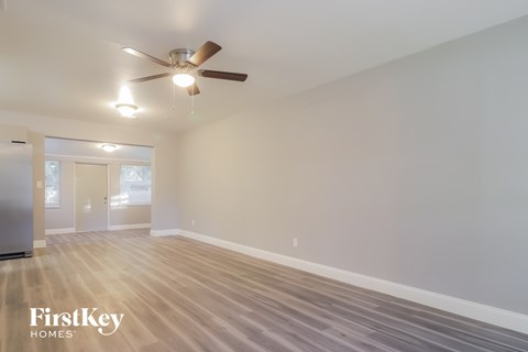 the spacious living room with ceiling fan and hardwood flooring