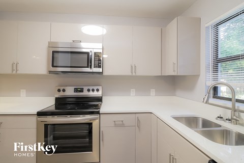 a kitchen with white cabinets and a stove and a sink