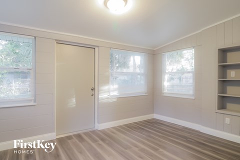 a living room with white walls and wood flooring and a door to a closet