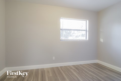 a bedroom with a window and wooden floors