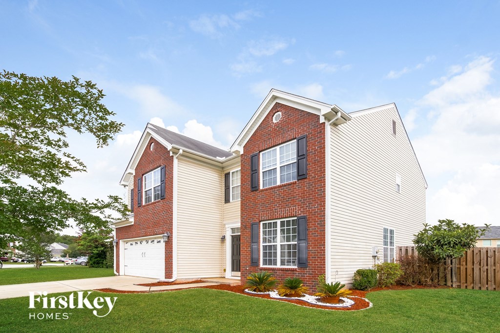 A brick house with a white garage door and a white fence.