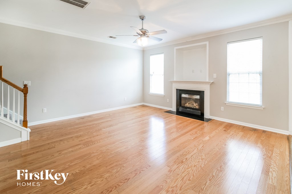 A spacious living room with a fireplace and wooden floors.