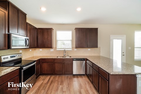 A kitchen with brown cabinets and a granite countertop.