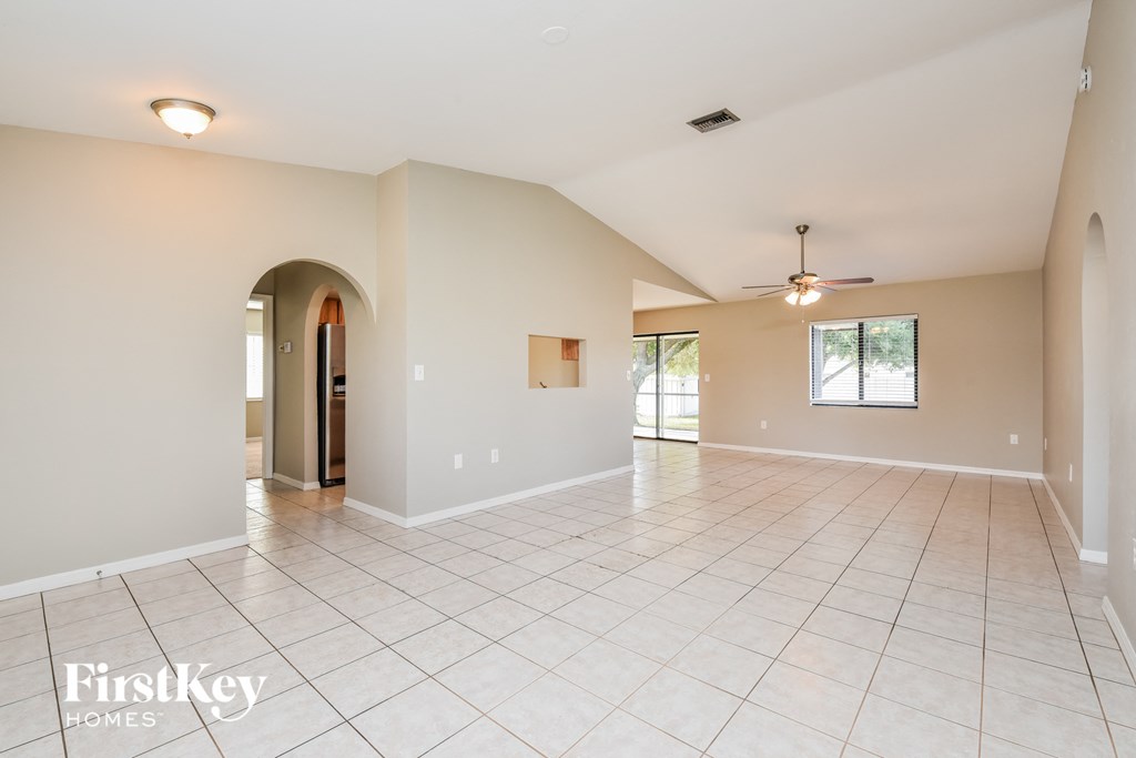 A spacious empty room with a tiled floor and a ceiling fan.