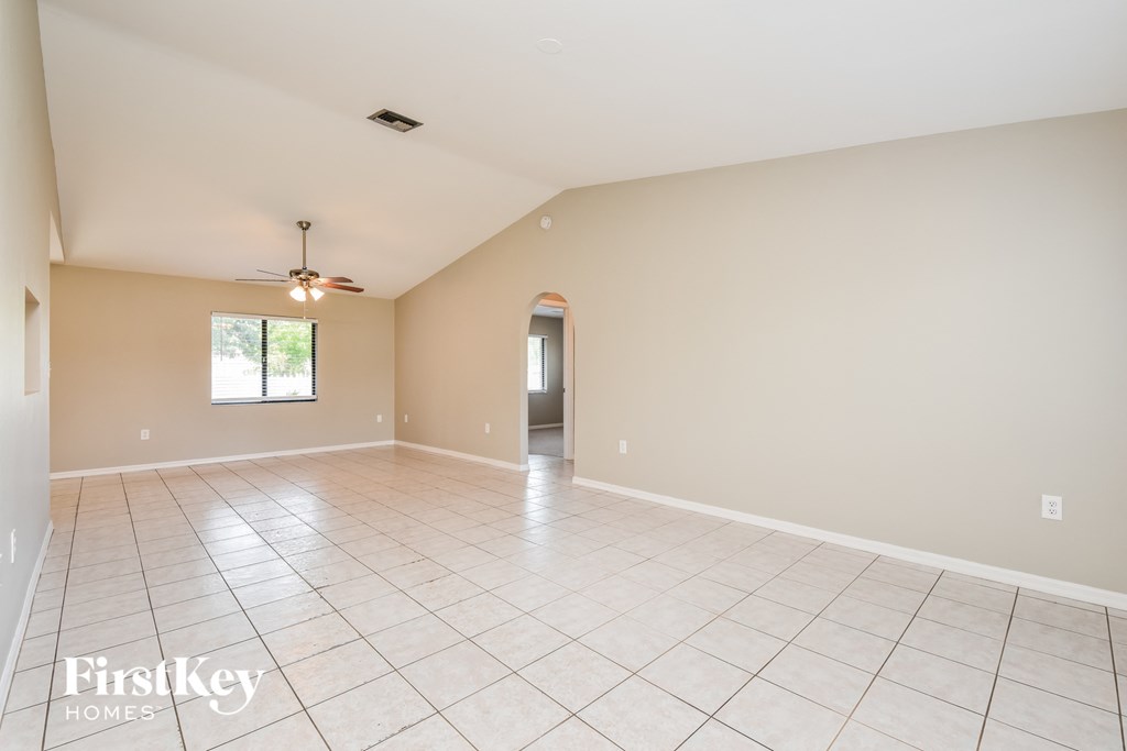 A spacious room with a tiled floor and a ceiling fan.