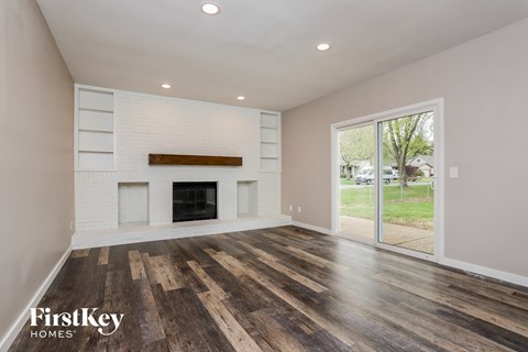 A spacious room with a fireplace and wood flooring.