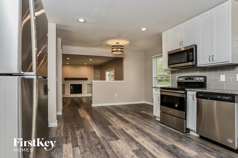 A kitchen with a stainless steel refrigerator and wooden floors.