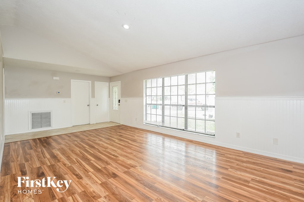 an empty living room with wood floors and a large window