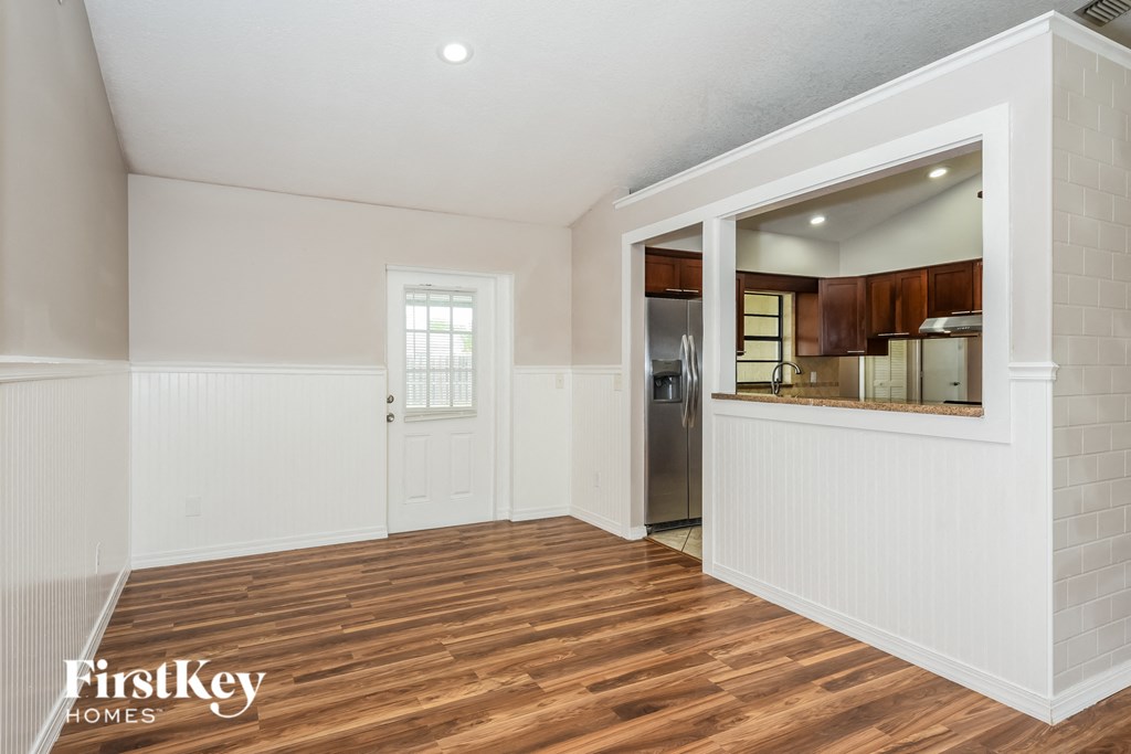 a living room with white walls and a door to a kitchen