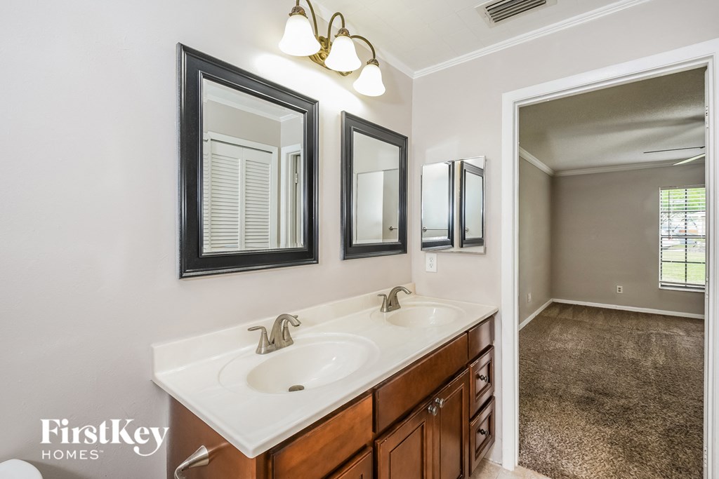 a bathroom with two sinks and two mirrors and a large window