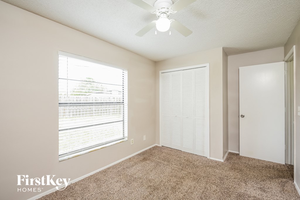 a spacious living room with a large window and a ceiling fan