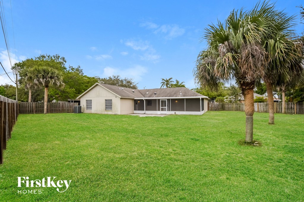 a house with a yard and palm trees in front of it