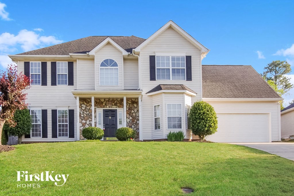 A large, well-maintained house with a stone facade and a large front yard.