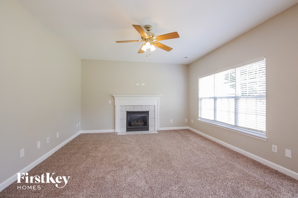 A spacious room with a fireplace and a ceiling fan.