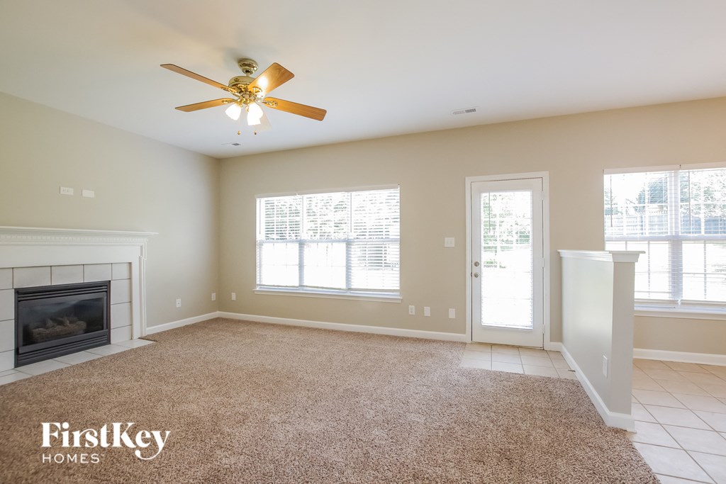 A spacious living room with a fireplace and a ceiling fan.