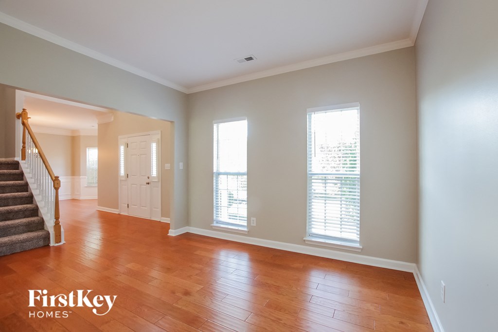A room with wooden floors and a staircase leading to another room.