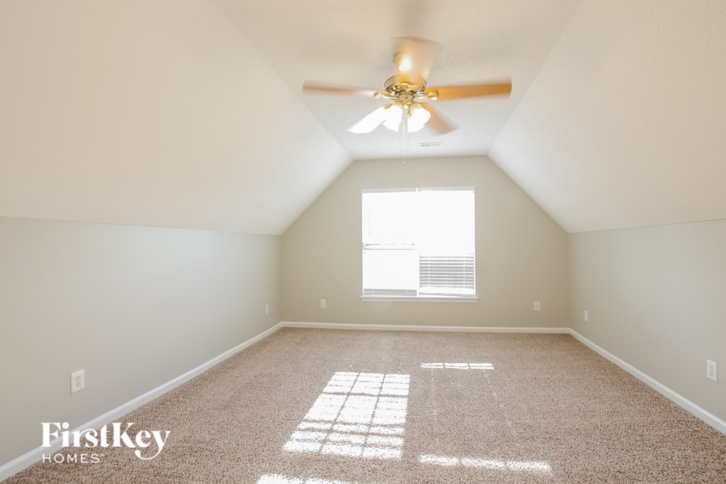 A room with a carpet and a ceiling fan.