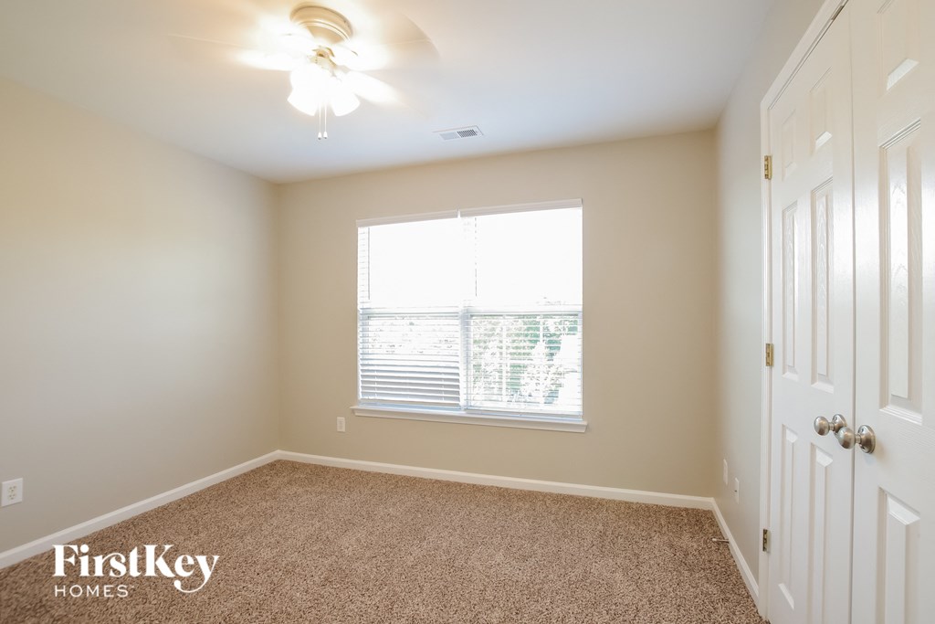 A room with a carpeted floor and a ceiling fan.