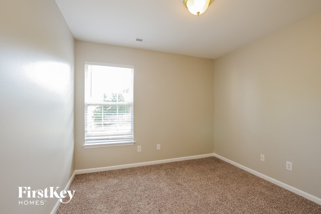 A room with a carpeted floor and a window with blinds.
