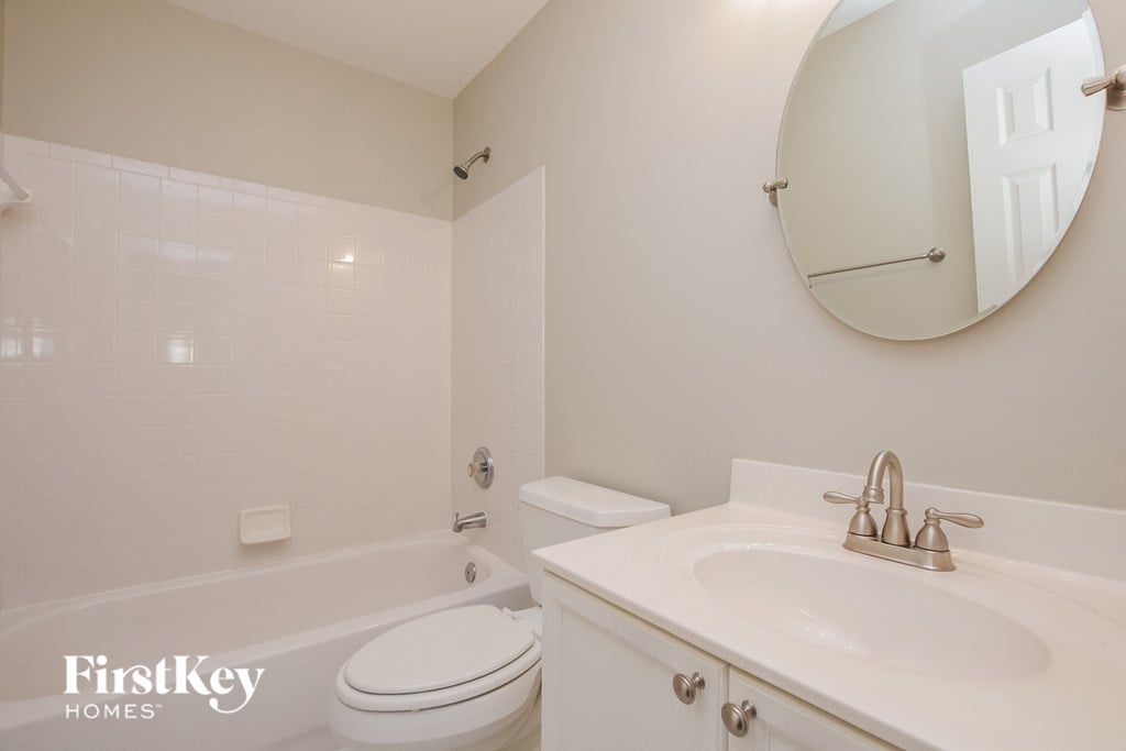 A white bathroom with a toilet, sink and mirror.