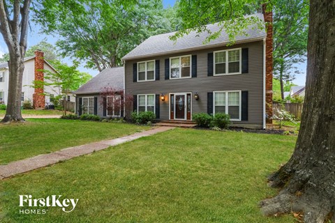 a house with a lawn and trees in front of it