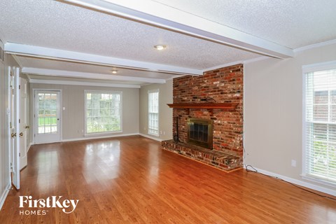 a living room with a brick fireplace and wooden floors