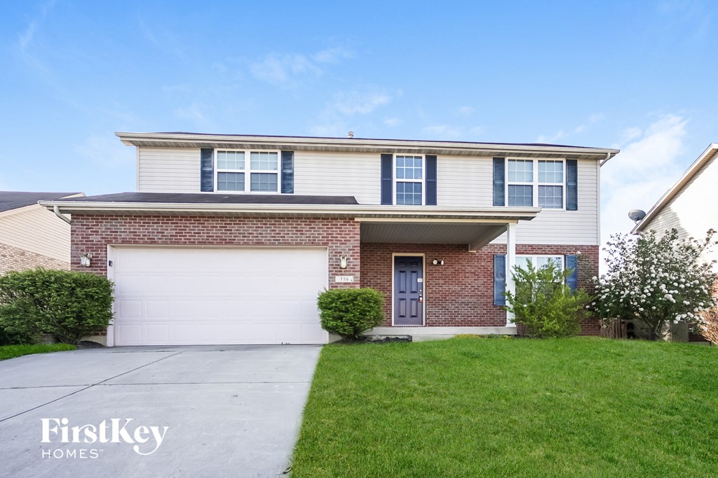 a brick house with a white garage door and a lawn