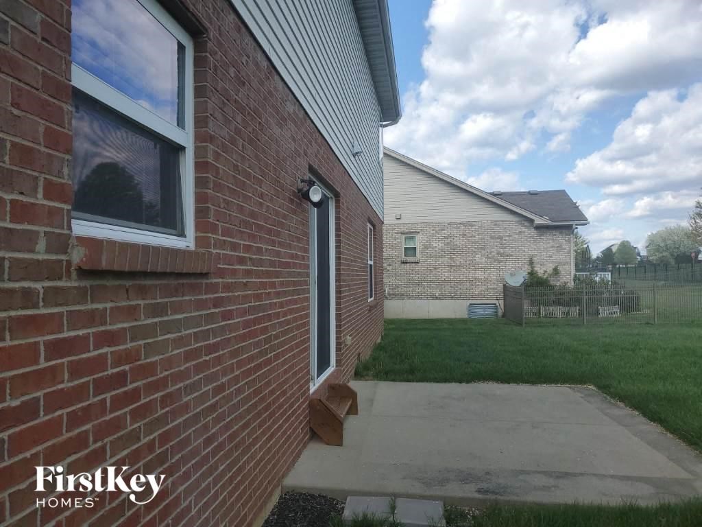 the side of a brick house with a sidewalk and grass