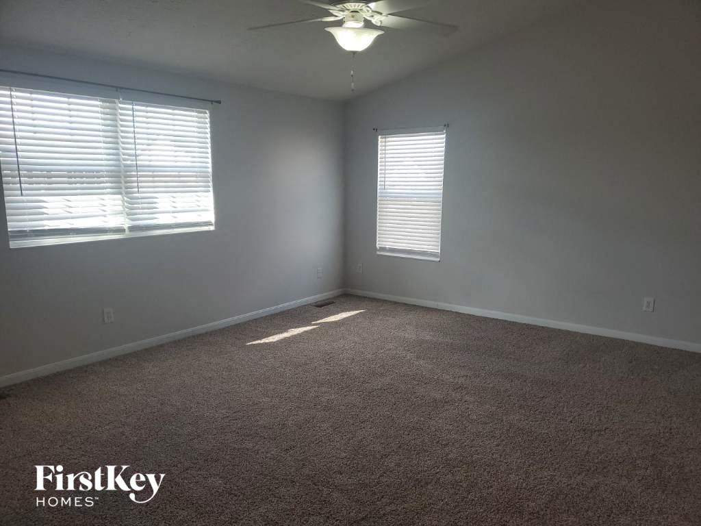 an empty room with a ceiling fan and two windows