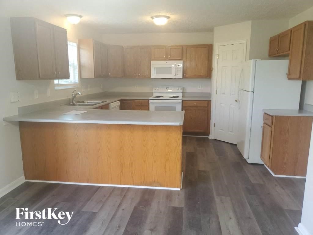 an empty kitchen with wooden cabinets and a white refrigerator