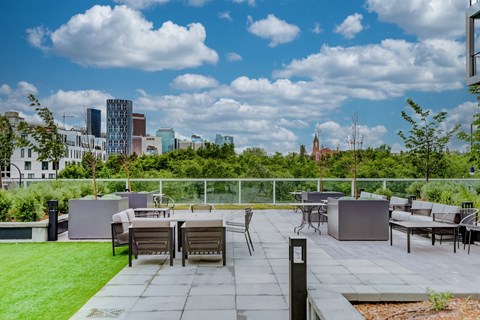 A rooftop patio with a table and chairs overlooking a city skyline.